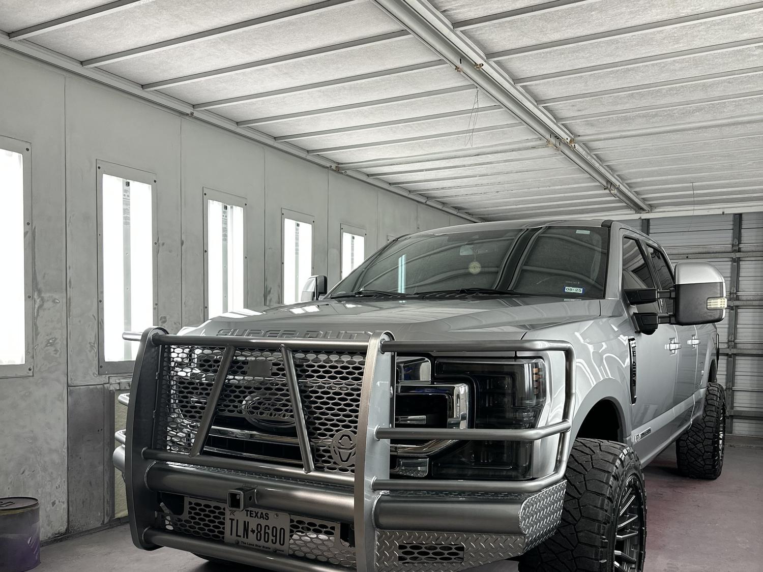A lifted Ford Super Duty crew cab inside the spray booth at Larry's Paint & Body Shop