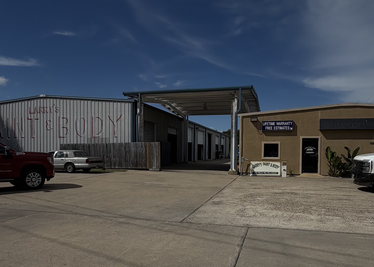The front of Larry's Paint & Body Shop on West Market Street in Rockport, Texas: the painted PAINT & BODY sign, the open drive-through bays and the office